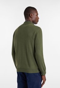 Ciemnozielony sweter pleciony z ko�łnierzem, długimi rękawami oraz ściągaczami przy mankietach i dole; miękka struktura i bezszwowy design.