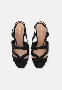 Sandales ouvertes noires pour femmes avec plusieurs brides et boucle à la cheville, semelle plate, vues de dessus sur fond blanc.