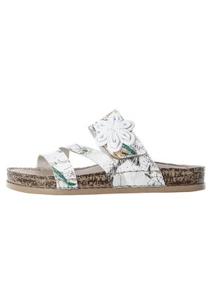 Slide sandal with white textured straps featuring a floral accent. Cork-like sole with a brown, speckled finish. Flip-flop style, open toe.