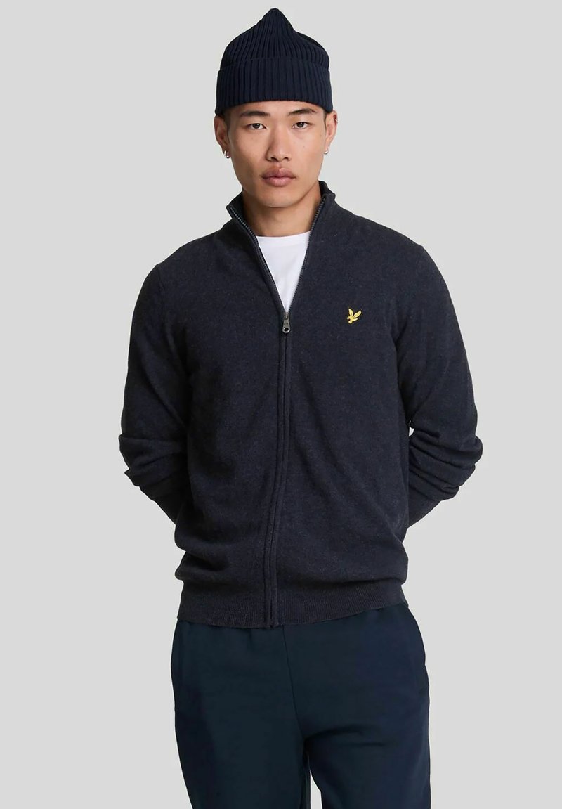 Cardigan blu navy con zip realizzato in misto lana. Presenta maniche lunghe, polsini a costine e un piccolo logo di un uccello ricamato in giallo sul petto.