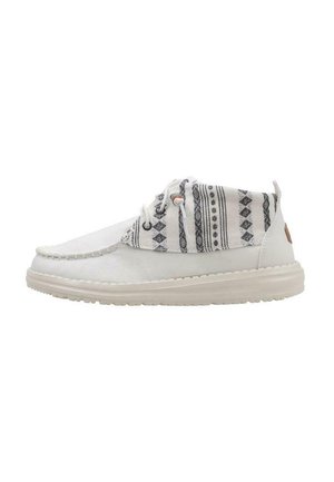 Chaussures décontractées blanches avec un dessus en tissu à motifs, semelle crémeuse texturée et motifs géométriques noirs contrastants sur le col.