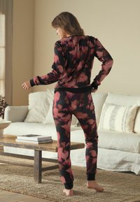 Floral-patterned loungewear set in shades of pink and black, featuring ribbed fabric, long sleeves, and fitted cuffs. Soft texture, relaxed fit.
