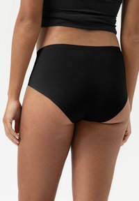 Hooggewaist zwarte onderbroek van gladde stof, naadloos ontwerp en gematigde bedekking, met een zachte elastische tailleband.