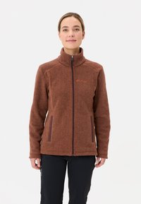 Bruine fleece jas met hoge kraag, ritssluiting aan de voorkant en twee zijzakken. Inclusief een subtiele logo op de linkerborst en een gestructureerde stof.