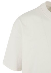 T-shirt med korte ærmer og rund hals i off-white stof. Blød bomuldsstruktur med en glat overflade og et minimalistisk design, der har rene kanter.