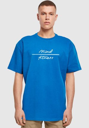 Blå bomulds T-shirt med korte ærmer og rund hals. Forsiden viser hvid tekst: "Mind fitness" med en vandret linje.
