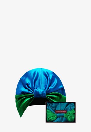 Turban en soie bleu royal et vert, présentant un design noué sur le dessus et une section inférieure contrastante. Livré dans un emballage assorti.