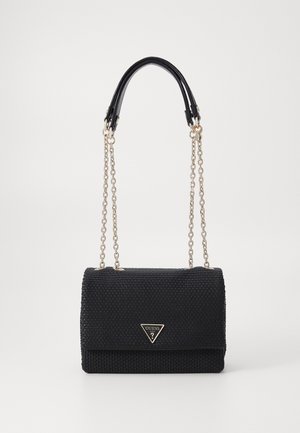 Sac à épaule noir texturé avec des bandoulières en chaîne dorée et un logo GUESS triangulaire sur le rabat avant, sur un fond neutre.