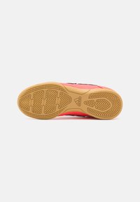 Zapatilla deportiva con una parte superior sintética rosa y acentos negros. Cuenta con una suela de goma texturizada y un dibujo en el relieve para mayor agarre.