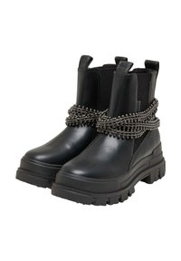 Black leather ankle boots with elastic side panels, chunky rubber soles, and metallic chain detail wrapped around the shaft.