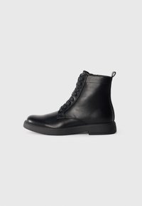 Botas de cuero negras hasta el tobillo con punta redondeada, cierre con cordones en la parte delantera y un tacón bajo cuadrado. Textura suave y tirador en la parte trasera.