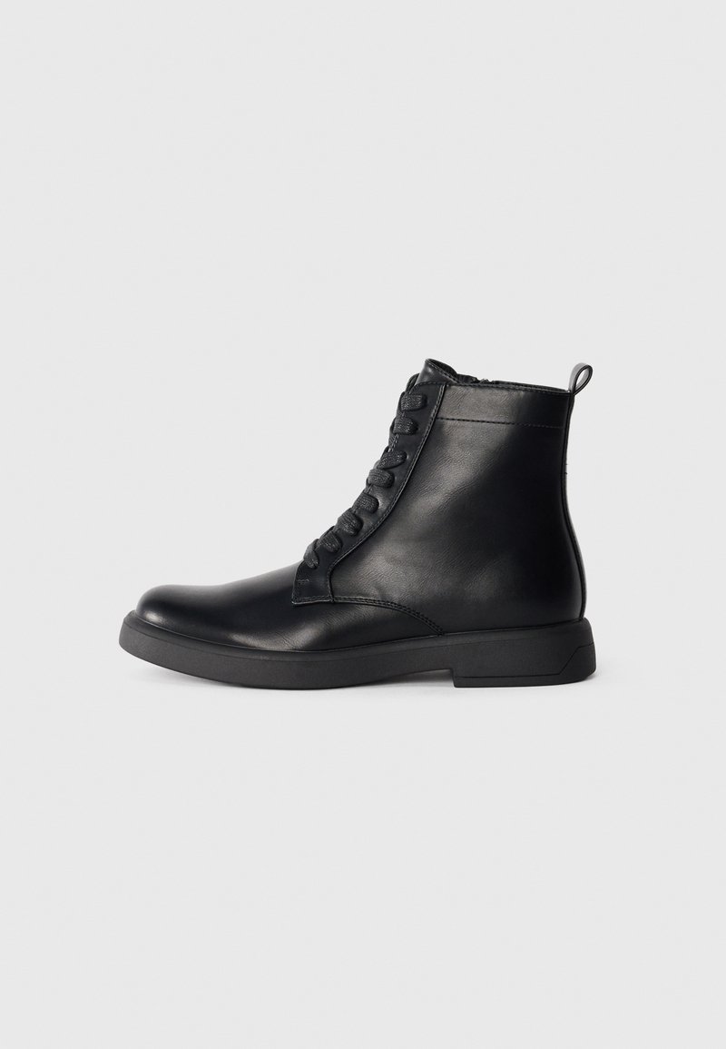 Botas de cuero negras hasta el tobillo con punta redondeada, cierre con cordones en la parte delantera y un tacón bajo cuadrado. Textura suave y tirador en la parte trasera.