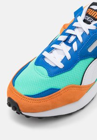 Sneaker atletica con parte superiore in mesh e suede blu, verde e arancione. Caratterizzato da lacci bianchi, dettaglio del logo e suola in gomma nera.