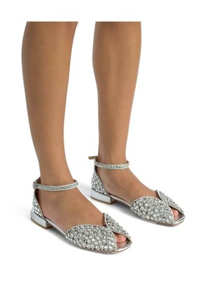 Infradito piatti argento con decorazioni in strass, design aperto sulla punta, cinturino alla caviglia e tacco basso. Parte superiore testurizzata con accenti brillanti.