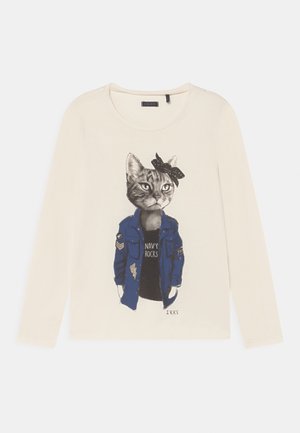 Hvid langærmet skjorte med grafik af en kat iført en blå jakke, sort skjorte med teksten "Navy Rocks" og en sort polkaprikket sløjfe på hovedet.