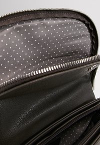 Borsa in pelle nera con zip argentata, caratterizzata da un esterno liscia e un interno foderato con pois grigi. Presenta più scomparti per una facile organizzazione.