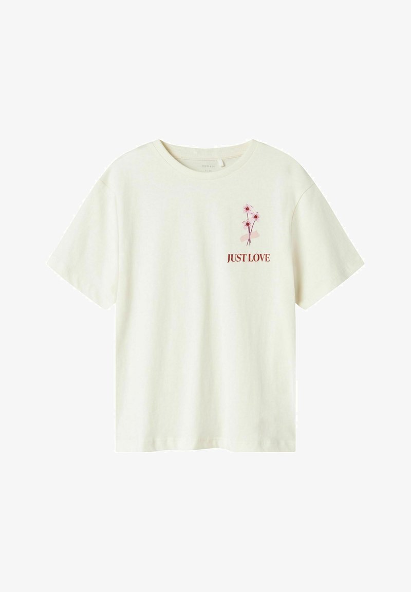 Camiseta de algodón color crema con mangas cortas. Presenta un pequeño diseño floral y el texto "JUST LOVE" en color burdeos en la parte delantera.