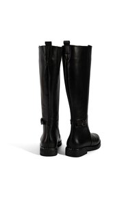 Schwarze Leder-Stiefel bis zum Knie mit glatter Textur, verstellbaren Riemen am Knöchel und niedrigem, gestapeltem Absatz.