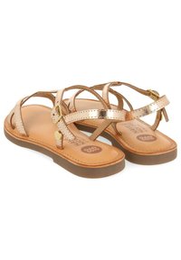 Sandali strappy in rosé metallico con suola piatta, dotati di una soletta marrone a contrasto e una fibbia laterale per la regolazione.