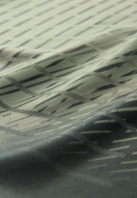 Close-up of gray fabric with diagonal and vertical black geometric lines and subtle folds creating texture.