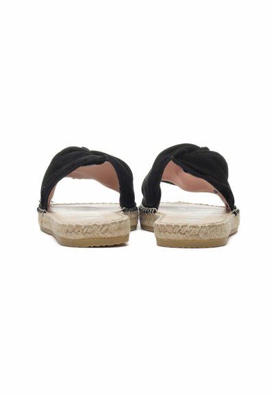 Espadrillas in suede nero con fasce superiori annodate, suola avvolta in juta beige e base in gomma piatta, che mostrano un design semplice e aperto.