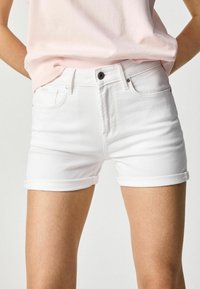 Shorts de mezclilla blanca con un diseño ajustado, puños enrollados, cinco bolsillos y un cierre de botón negro en la cintura. Textura suave.