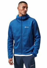 Blaue Fleecejacke mit Reißverschluss, strukturiertem Stoff, verstellbarer Kapuze und zwei Seitentaschen. Mit Logo auf der Brust und einer Tasche am Ärmel.