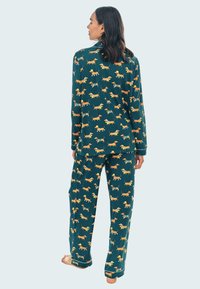 Conjunto de pijama de manga larga en tejido teal, con un patrón repetido de perritos salchicha en naranja y amarillo. Ajuste cómodo con pantalones holgados.