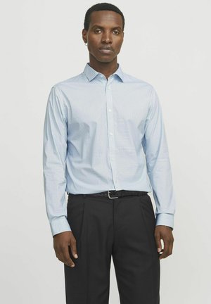 Camisa de botón azul claro con un pequeño patrón a cuadros, de mangas largas y cuello puntiagudo, combinada con pantalones negros.