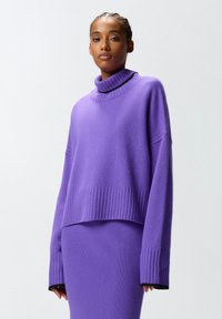 Maglione lavorato a maglia viola con un alto colletto a coste, maniche larghe e un design cropped. Tessuto testurizzato con dettagli a coste all'orlo e ai polsini.