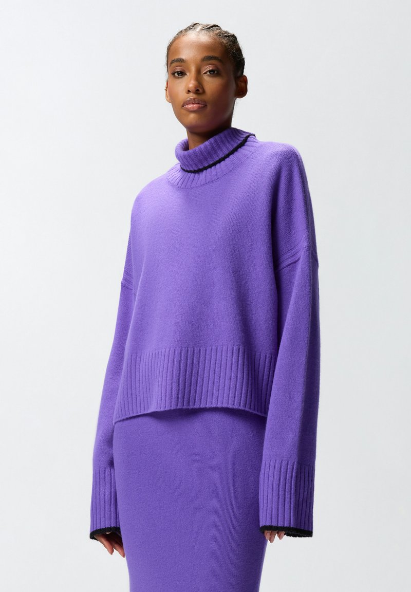 Maglione lavorato a maglia viola con un alto colletto a coste, maniche larghe e un design cropped. Tessuto testurizzato con dettagli a coste all'orlo e ai polsini.