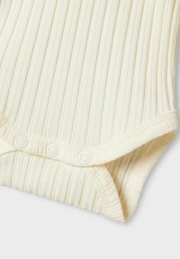 Kremowy bodysuit z prążkowanego materiału, z krótkimi rękawami, zapięciem na napy na dole oraz cienkimi pionowymi paskami dodającymi tekstury.