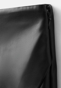 Czarna skórzana torba o teksturowanej powierzchni, z zamkiem błyskawicznym u góry i gładkim, subtelnie zakrzywionym kształcie.