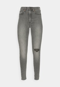 Jeans skinny grigi a vita alta in denim, con dettaglio di ginocchio consumato e silhouette aderente. Cuciture lungo le gambe.