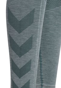 Leggings i en dämpad teal-färg med en texturerad yta. Har ett vertikalt chevronmönster i en ljusare nyans, med randiga detaljer.