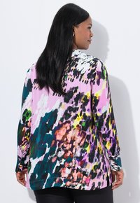 Colorful long-sleeve blouse in lightweight fabric, featuring an abstract print with pink, green, black, and yellow splashes, and side slits.