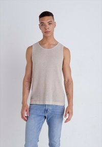 Beige ribbet tanktopp med rund hals, med en glatt tekstur og en avslappet passform, kombinert med lyseblå jeans.