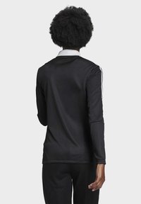 Long-sleeve black athletic shirt with a white collar and stripes on sleeves, made from smooth, lightweight fabric, fitted design at the back.