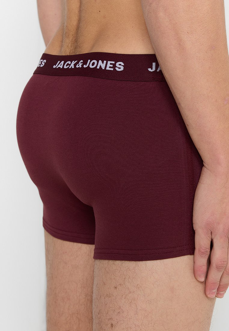 Hombre que lleva bóxers burdeos con cintura negra que presenta el logo "JACK & JONES" en blanco, mostrado desde atrás y de lado.