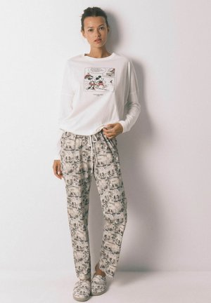 Camicia bianca a maniche lunghe con stampa grafica, abbinata a pantaloni da pigiama a fantasia colorata. Tessuto morbido, vestibilità rilassata, dotata di cintura con cordoncino.