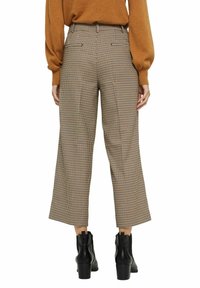 Breda, bruna och beige rutiga byxor med hög midja, sidofickor och en fåll som slutar strax ovanför vristen.