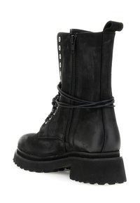 Zwarte leren veterlaarzen met een zijrits, dikke profielzool en gewikkelde veters om de enkel, in een schuine aanzicht.