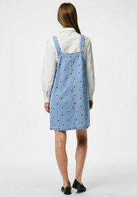 Jeanskangast seelik, millel on õlapaelad, helesinine värv, väikeste punaste lillemusteritega, kuni põlveni, sirge lõikega ja tagaküljel on taskud.