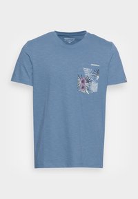 Světle modré bavlněné tričko s krátkým rukávem, které má na přední straně kapsu s květinovým vzorem v purpurové a zelené barvě.