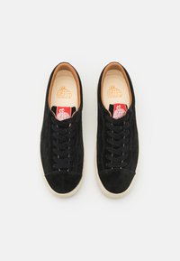 Schwarze Wildledersneaker mit abgerundetem Zehenbereich, schwarzen Schnürsenkeln und beiger Gummisohle; präsentiert das Markenlogo auf der Innensohle und der Zunge.
