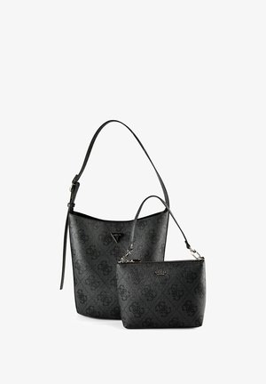 Zwei schwarze Guess-Taschen mit dunklem Monogramm-Muster; eine Bucket-Tasche mit langem Träger, eine kleinere Reißverschlusstasche mit kurzem Träger.