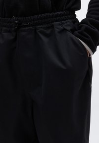 Μαύρο, ελαφρύ παντελόνι με ελαστική μέση, διαθέτει κορδόνι, πλαϊνές τσέπες και λεία υφή. Απλός, λειτουργικός σχεδιασμός.