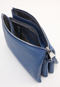 Modrá kožená kabelka s několika přihrádkami, s texturovaným povrchem, stříbrným kováním a bezpečným zipovým uzávěrem.