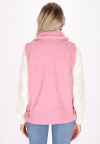 Rosa fleeceväst med h�ög krage och sidjusteringar, med krämfärgade stickade ärmar. Mjuk textur, avslappnad design.