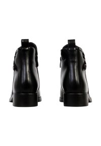 Bottines en cuir noir avec bouts arrondis, texture lisse, petit talon bloc et boutons décoratifs sur les côtés.